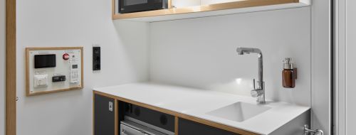 Die Küchenzeile im Büro hat einen Wasserhahn und einen Kühlschrank.